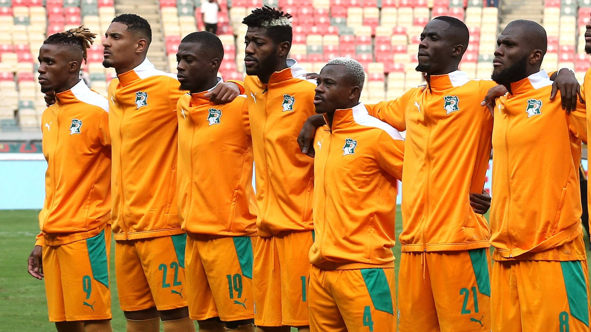 Ivory Coast Players In Orange Jacket Background