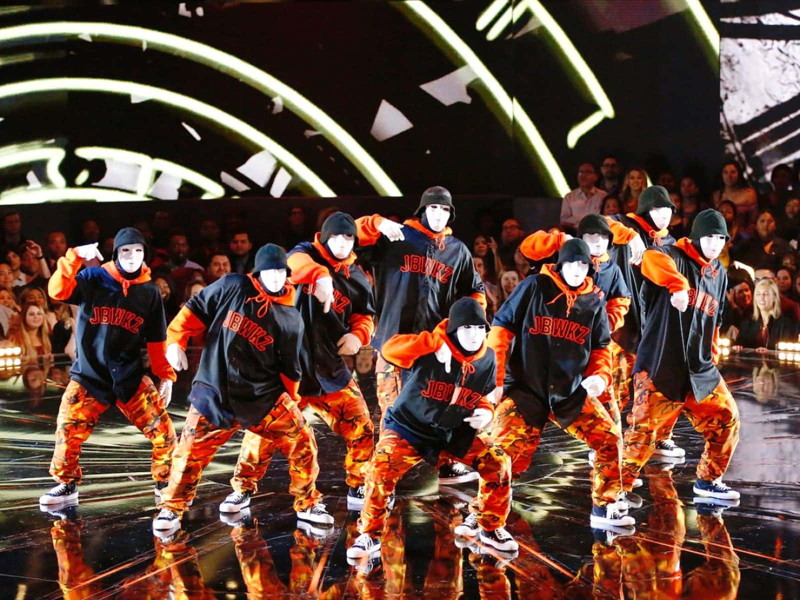 Engruppe Dansere Iført Orange Og Sorte Kostumer. Wallpaper
