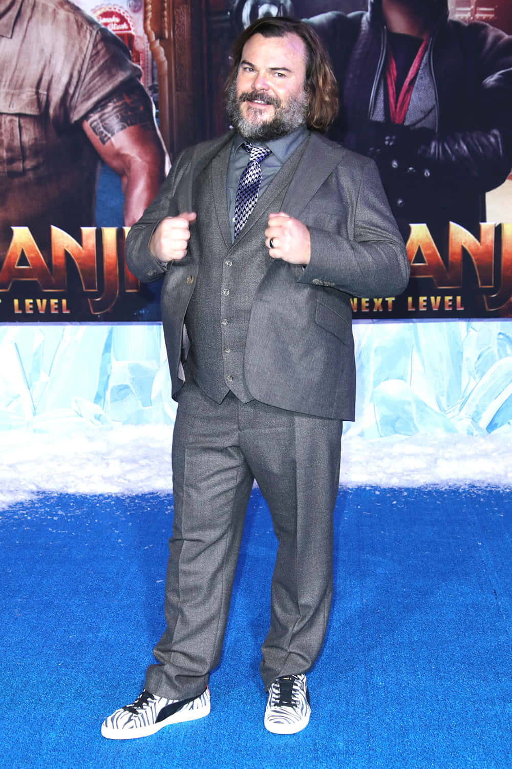 jack black Wallpaper — Jack Black in a gray suit and zebra-print sneakers poses confidently on a blue carpet at the 'Jumanji: Next Level' premiere.