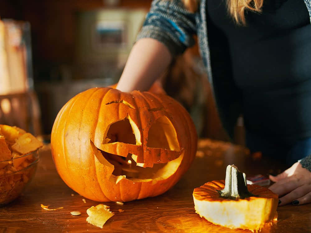 A Woman Carving A Pumpkin On A Table