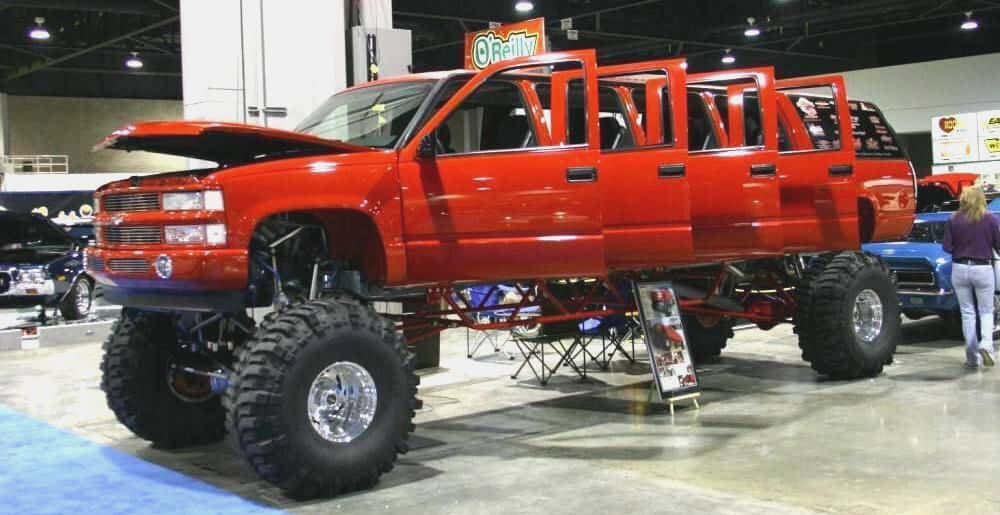 A Red Truck With Large Tires On Display At A Show Wallpaper