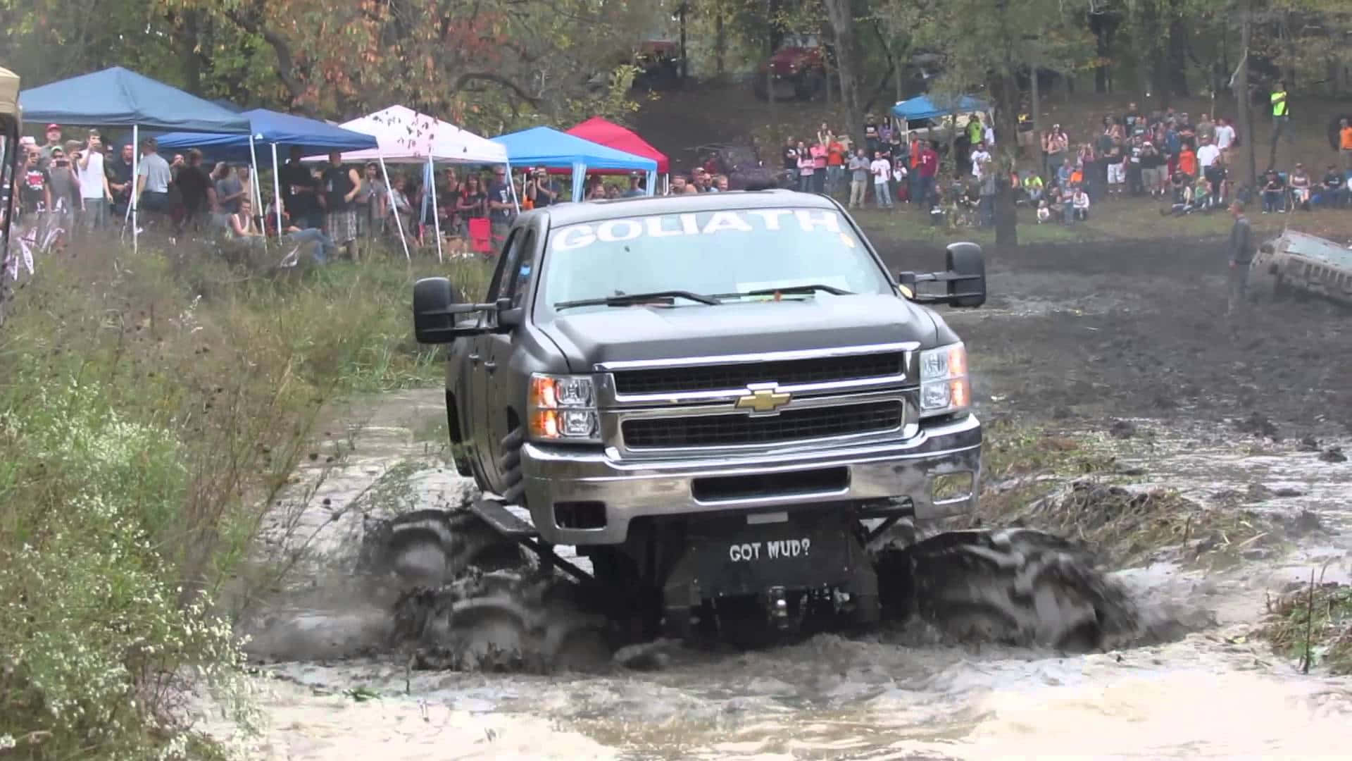 A Truck Driving Through Mud At A Festival Wallpaper