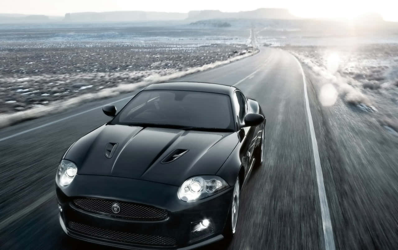 Stunning Jaguar XKR in motion on a picturesque road Wallpaper