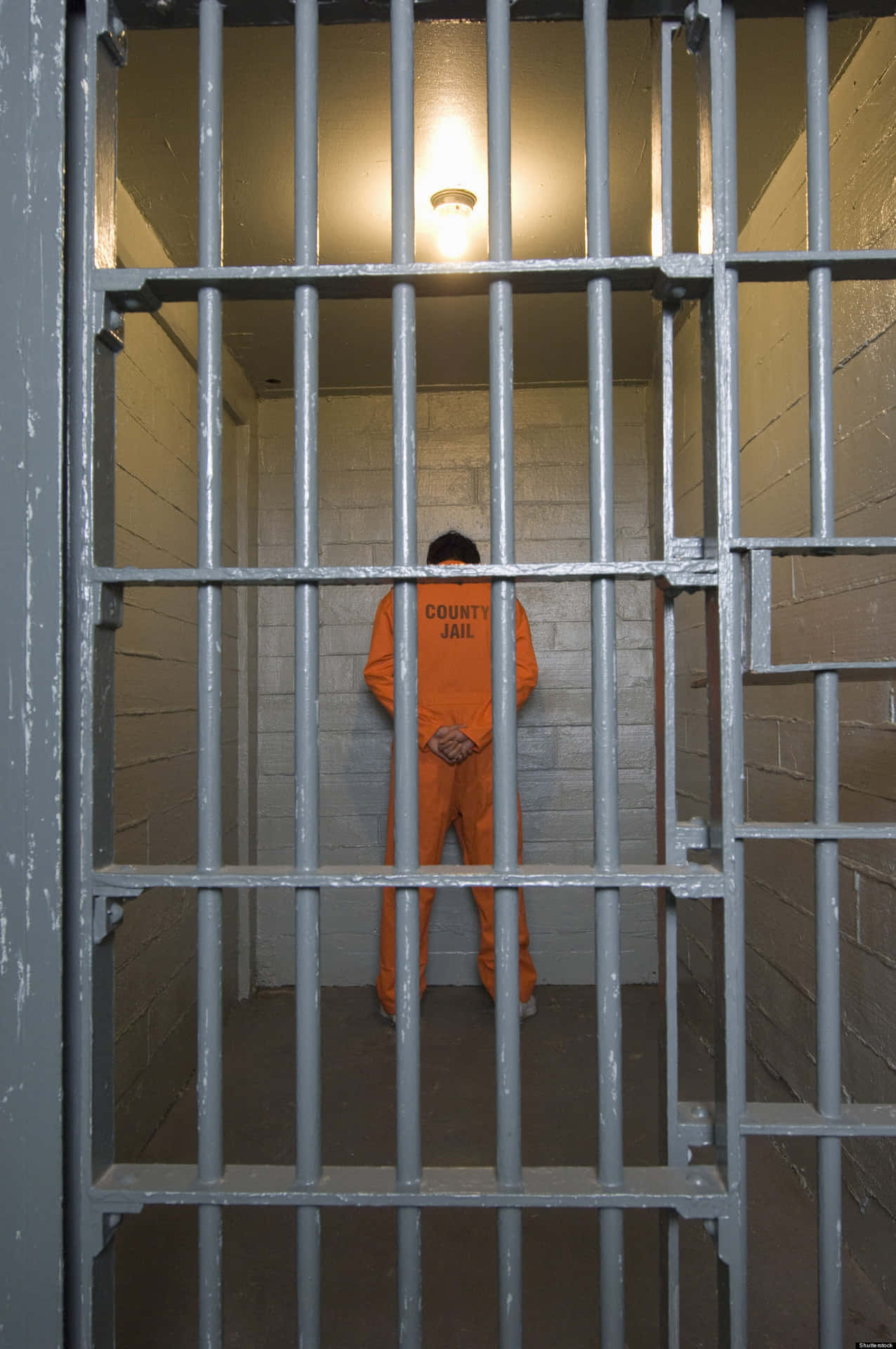 En mand i en orange fængselsdragt står i skyggerne