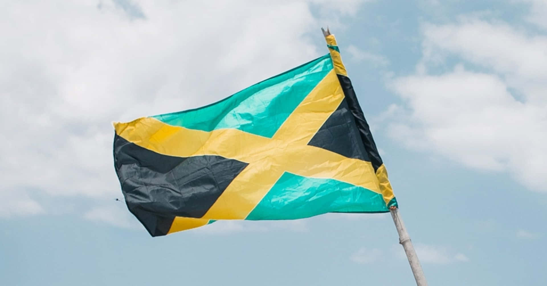 Jamaican Flag Waving Against Sky Wallpaper