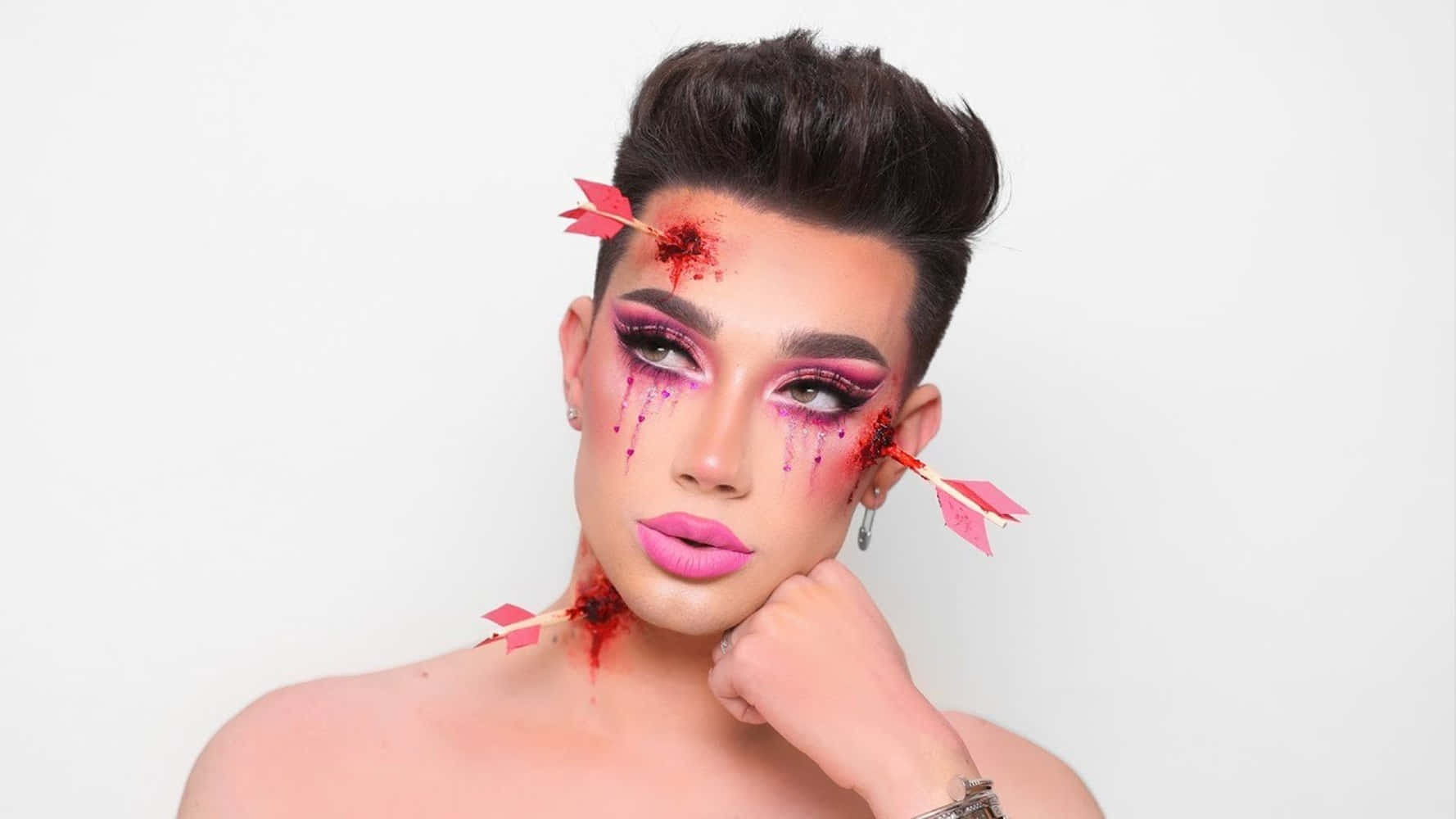 En mand med pink makeup og pile på hans ansigt. Wallpaper