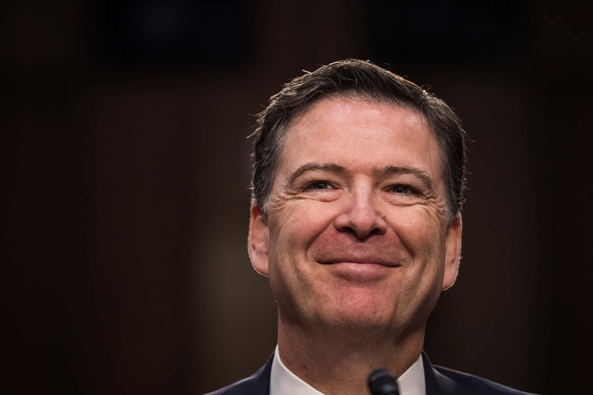 James Comey Smiling During Testimony Wallpaper