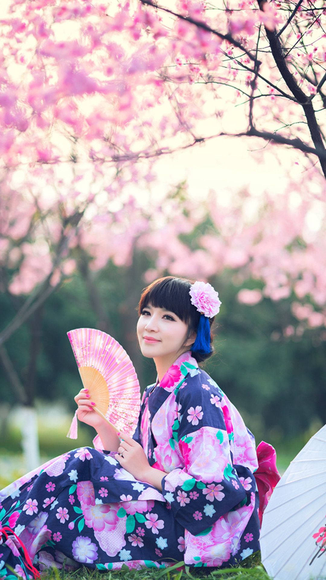 Chicajaponesa En Yukata Floral Junto A Un Árbol De Sakura. Fondo de pantalla