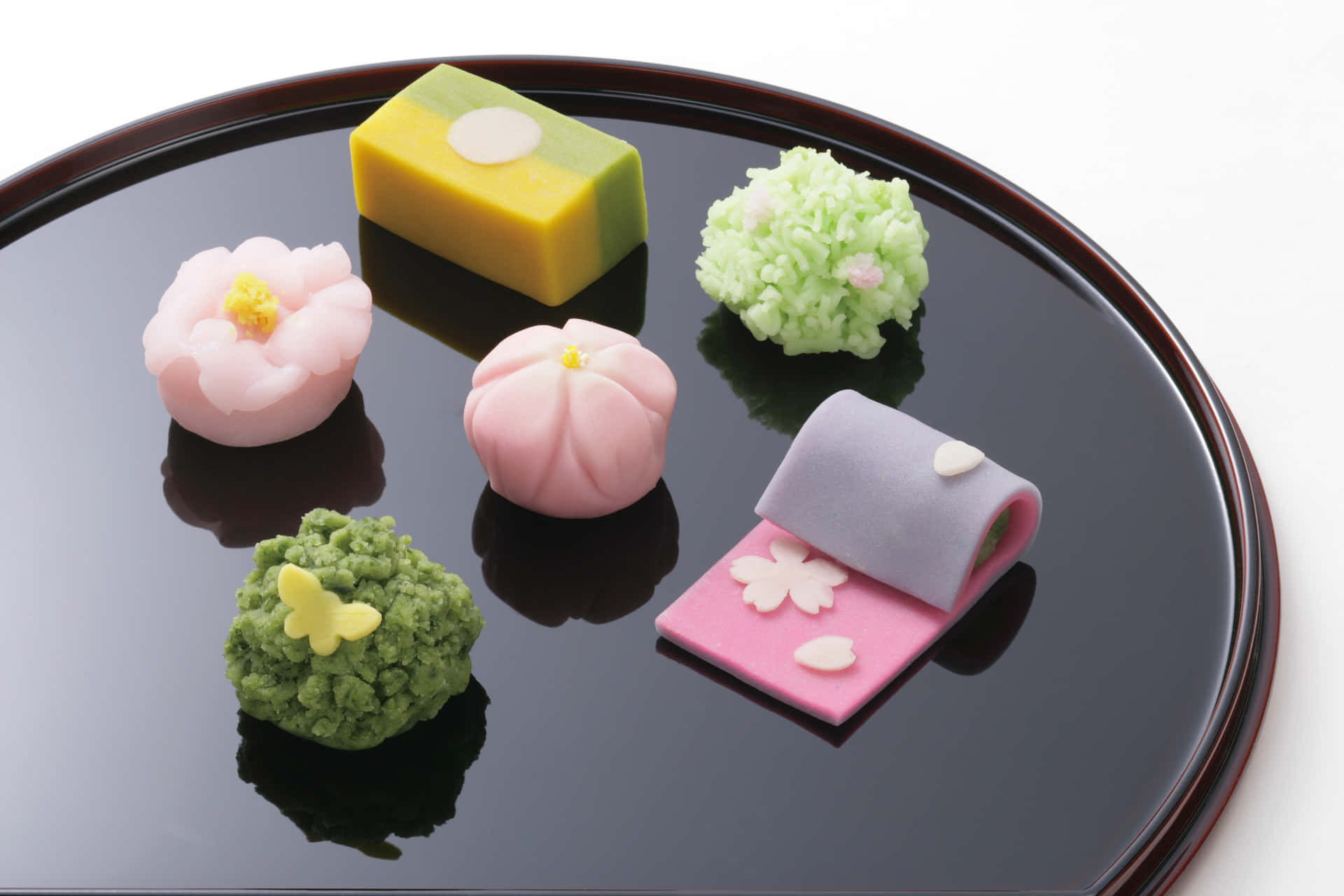 A delightful variety of colorful Japanese sweets served on elegant dishes. Wallpaper