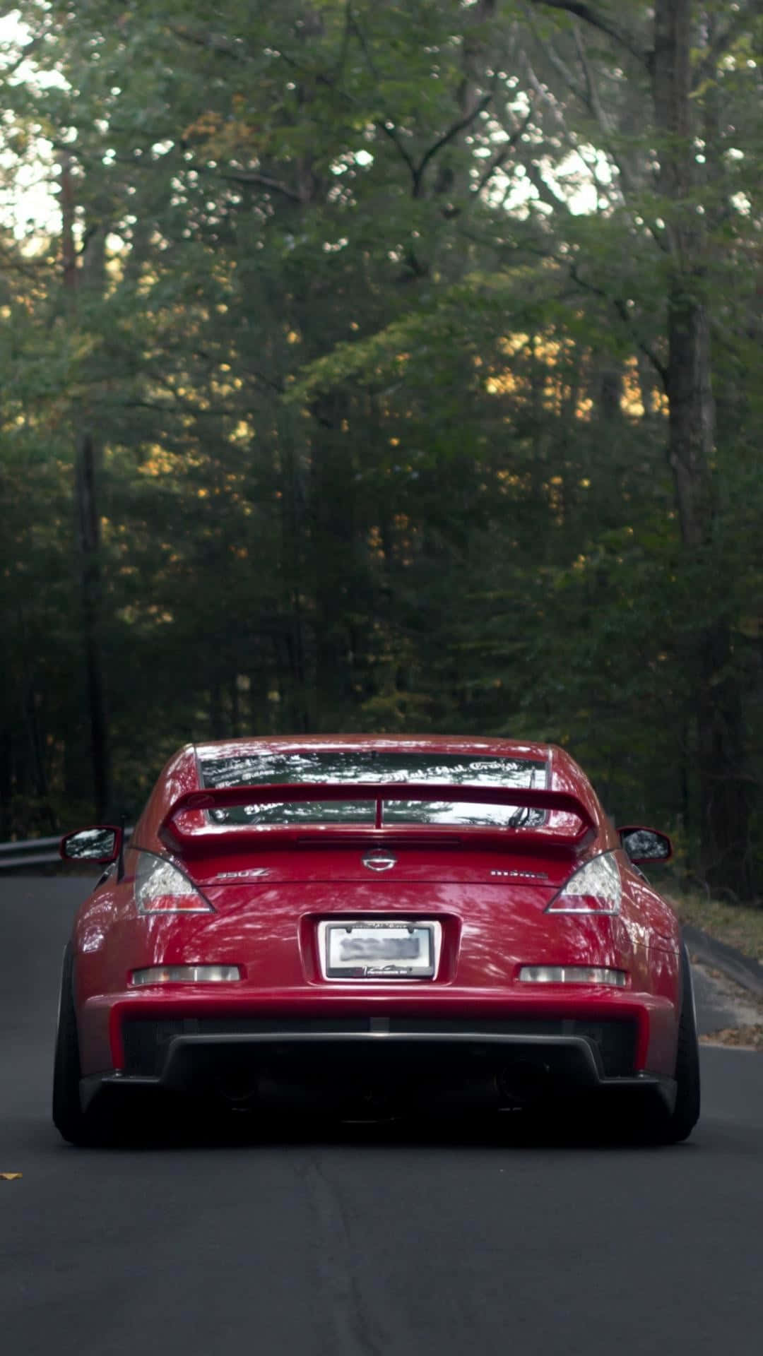 A Red Sports Car Driving Down A Road Wallpaper