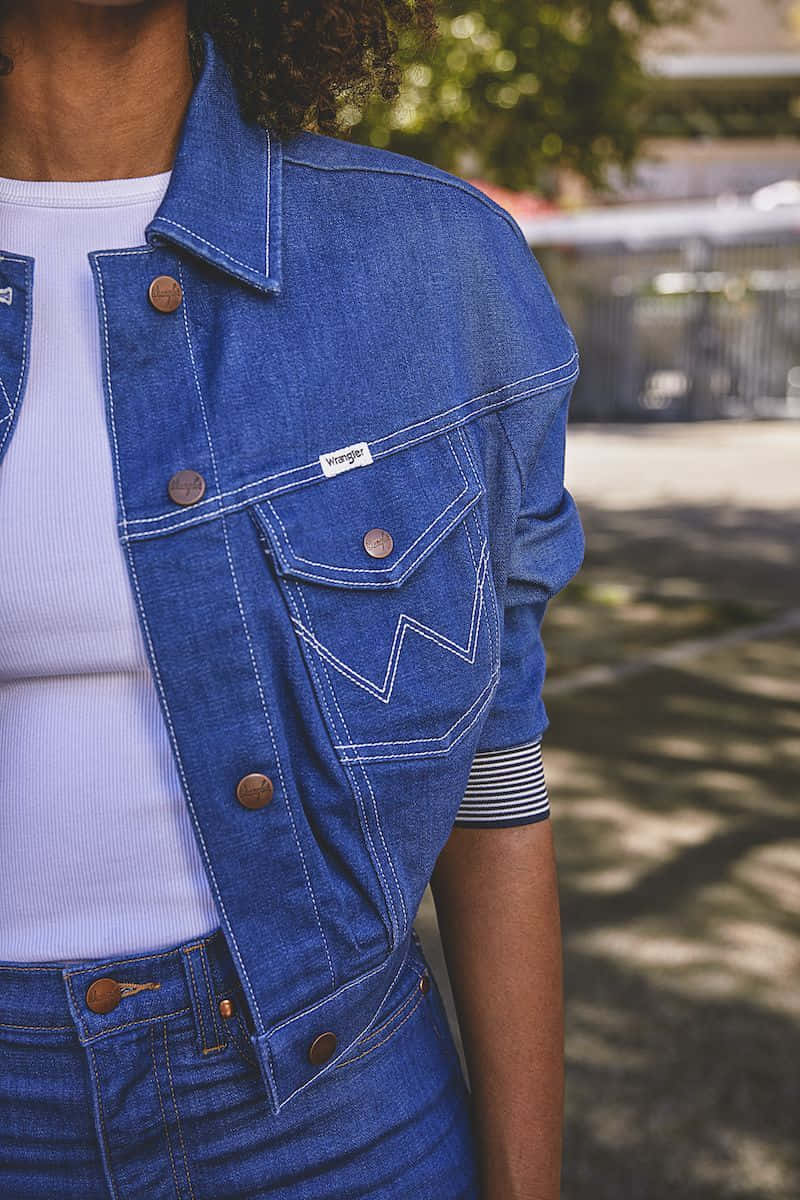 A Woman Wearing A Denim Jacket And Jeans