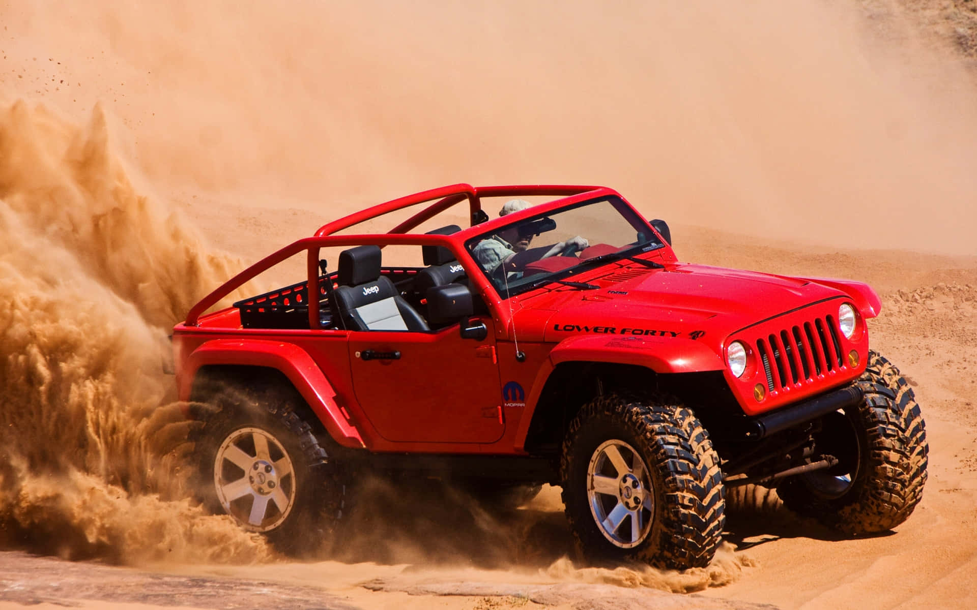 A Red Jeep Is Driving Through A Desert