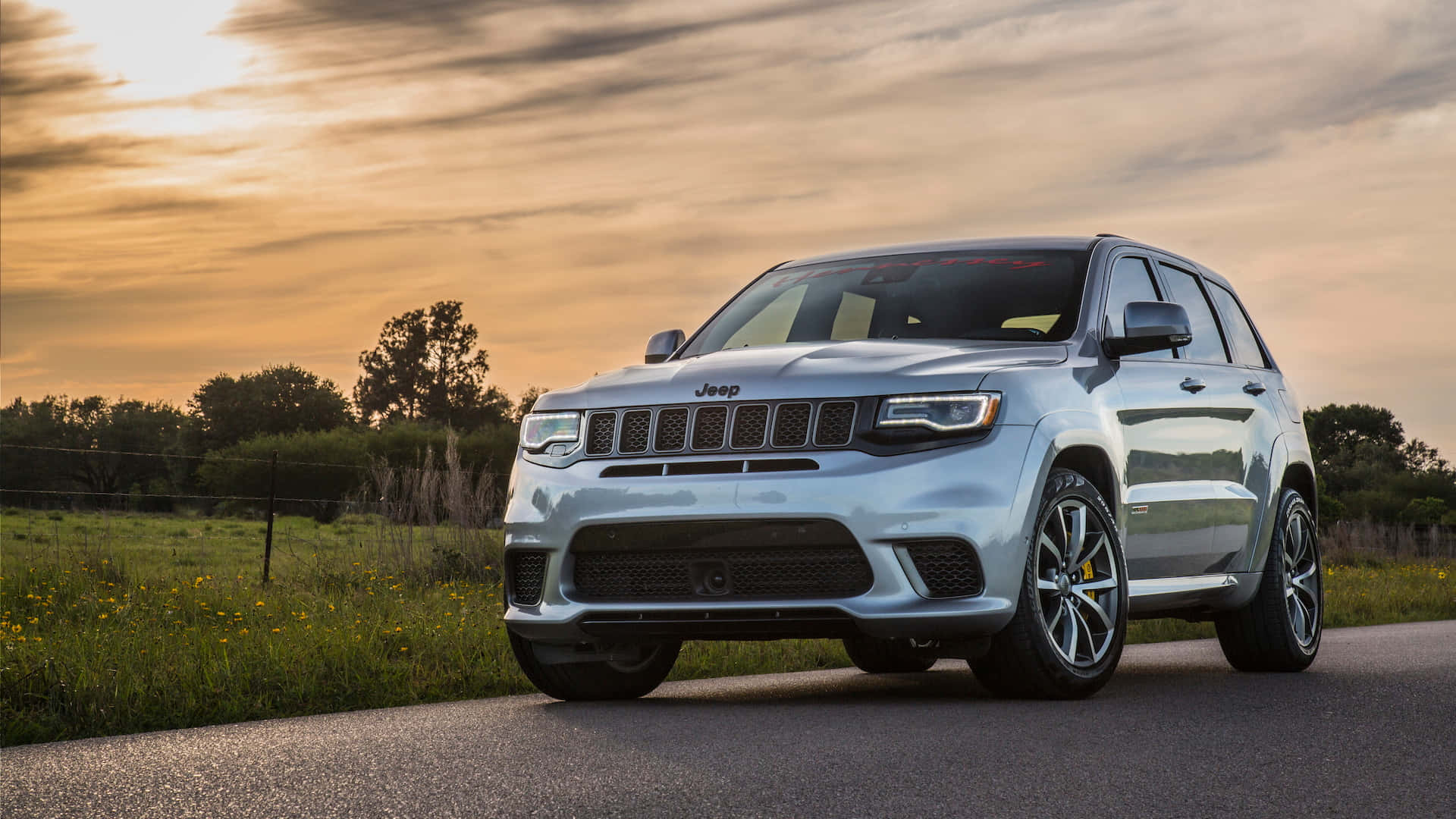The 2019 Jeep Grand Cherokee Is Driving Down A Country Road Wallpaper