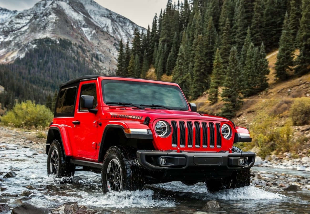 The Red Jeep Wrangler Is Driving Through A River
