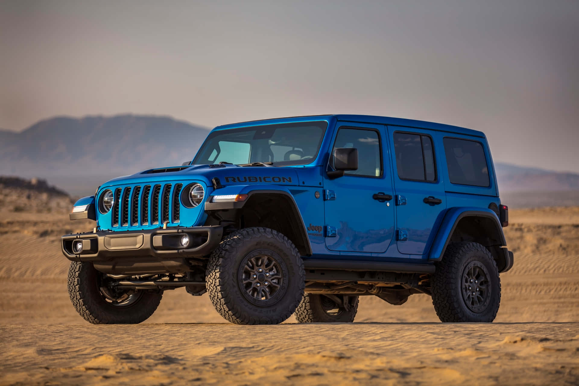 A Blue Jeep Wrangler Is Parked In The Desert