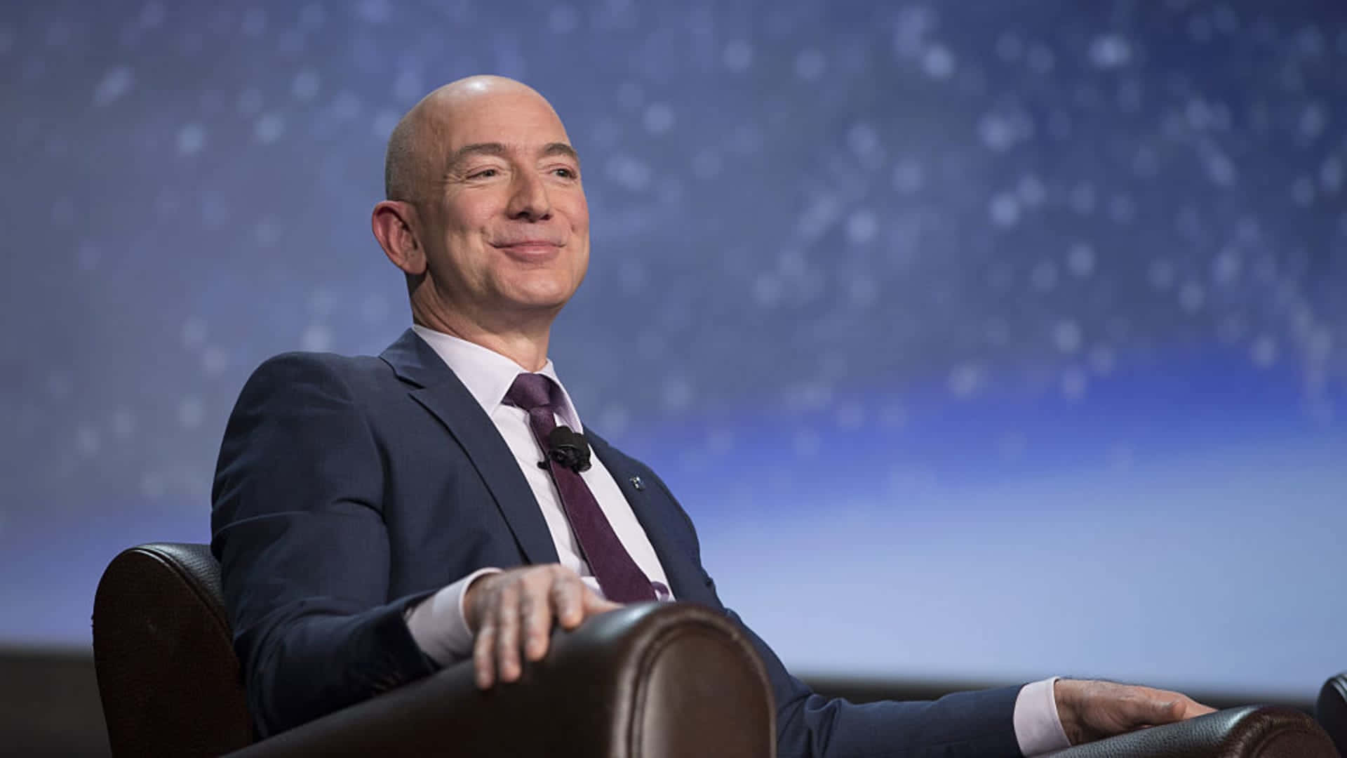 Jeff Bezos, Founder of Amazon, Smiling Against a Blue Background