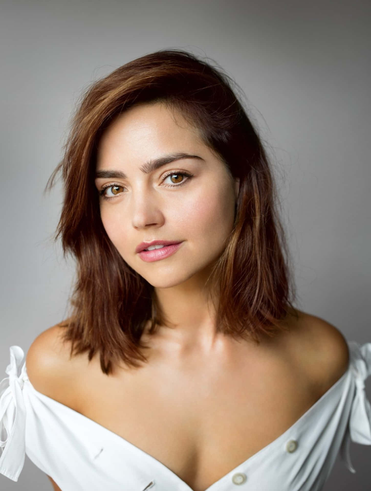 Jenna Coleman poses elegantly against a simple backdrop Wallpaper