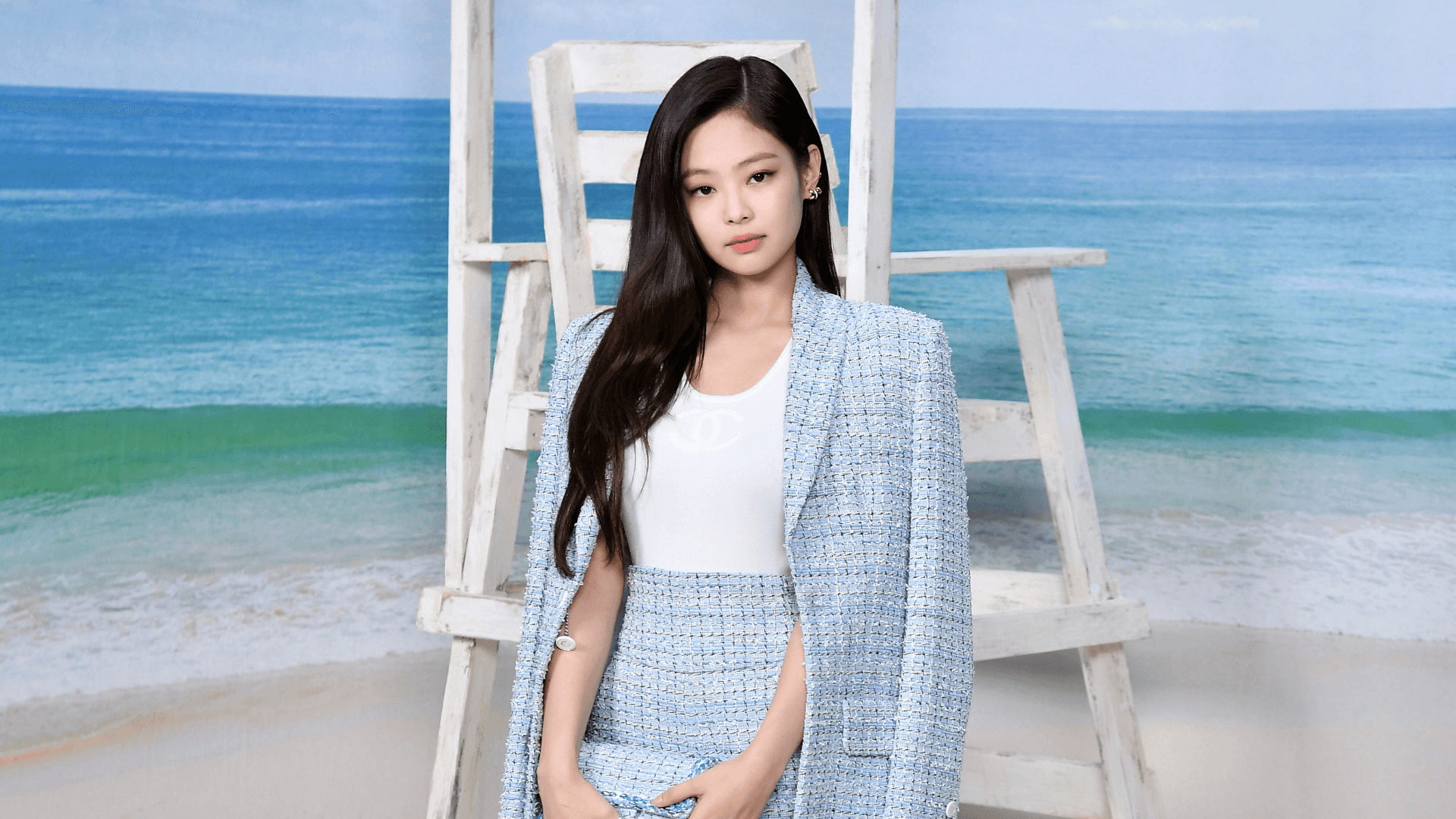 A Woman In A Blue Tweed Suit Standing On A Beach Chair
