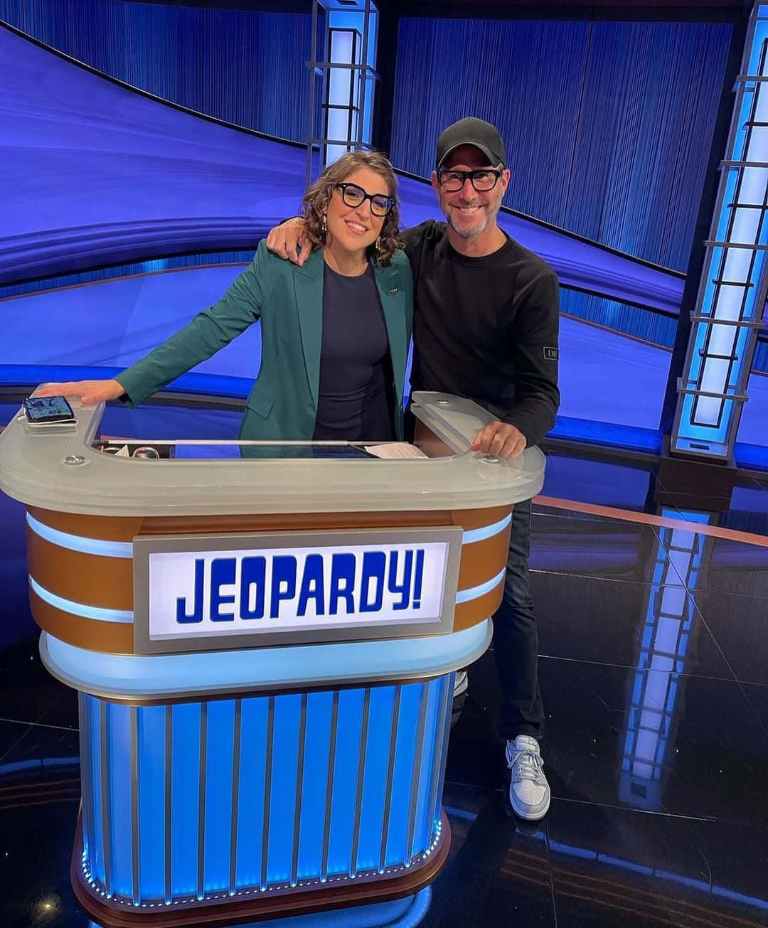 Two People Standing In Front Of A Jeopardy Board