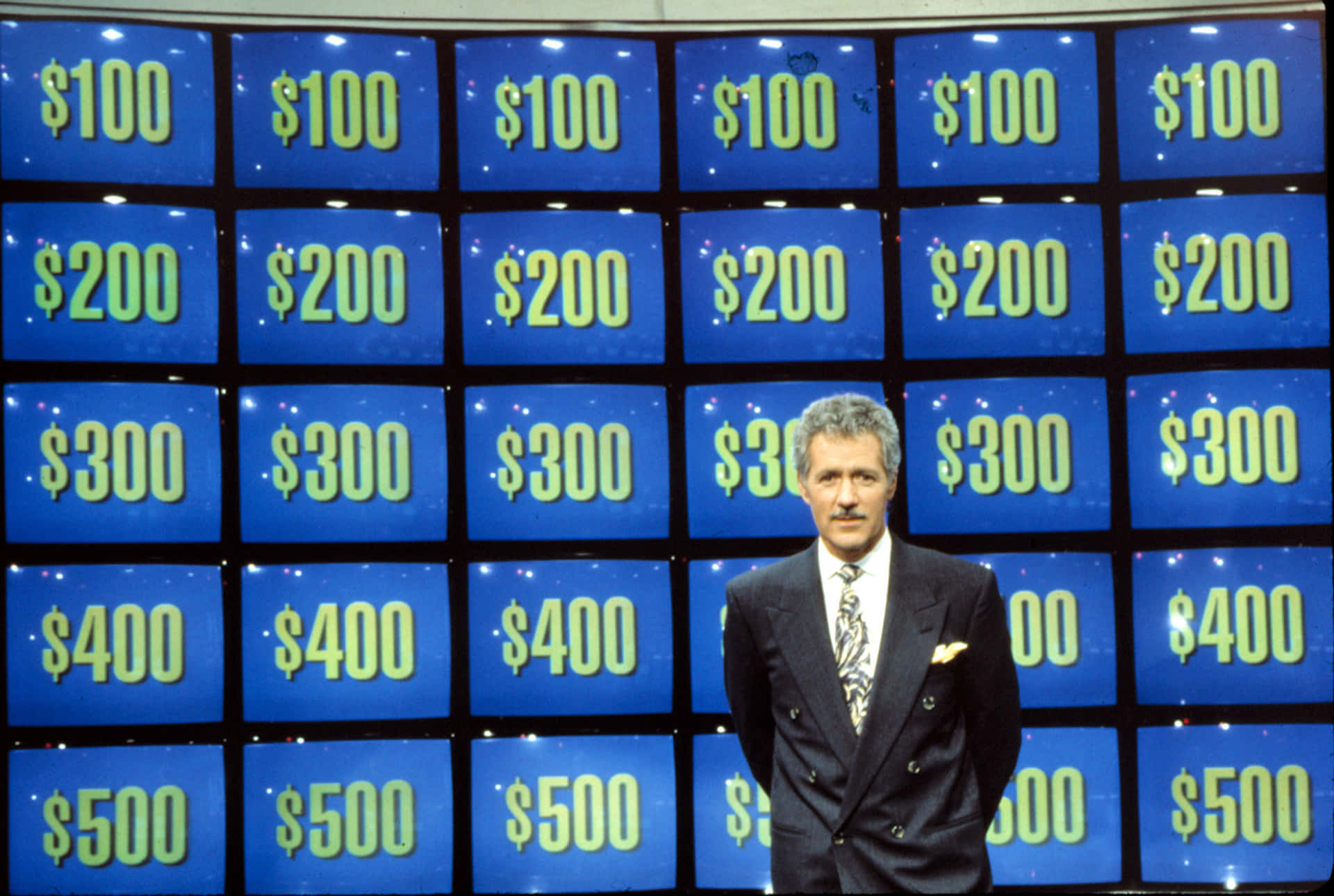 A Man Standing In Front Of A Large Screen With A Dollar Sign