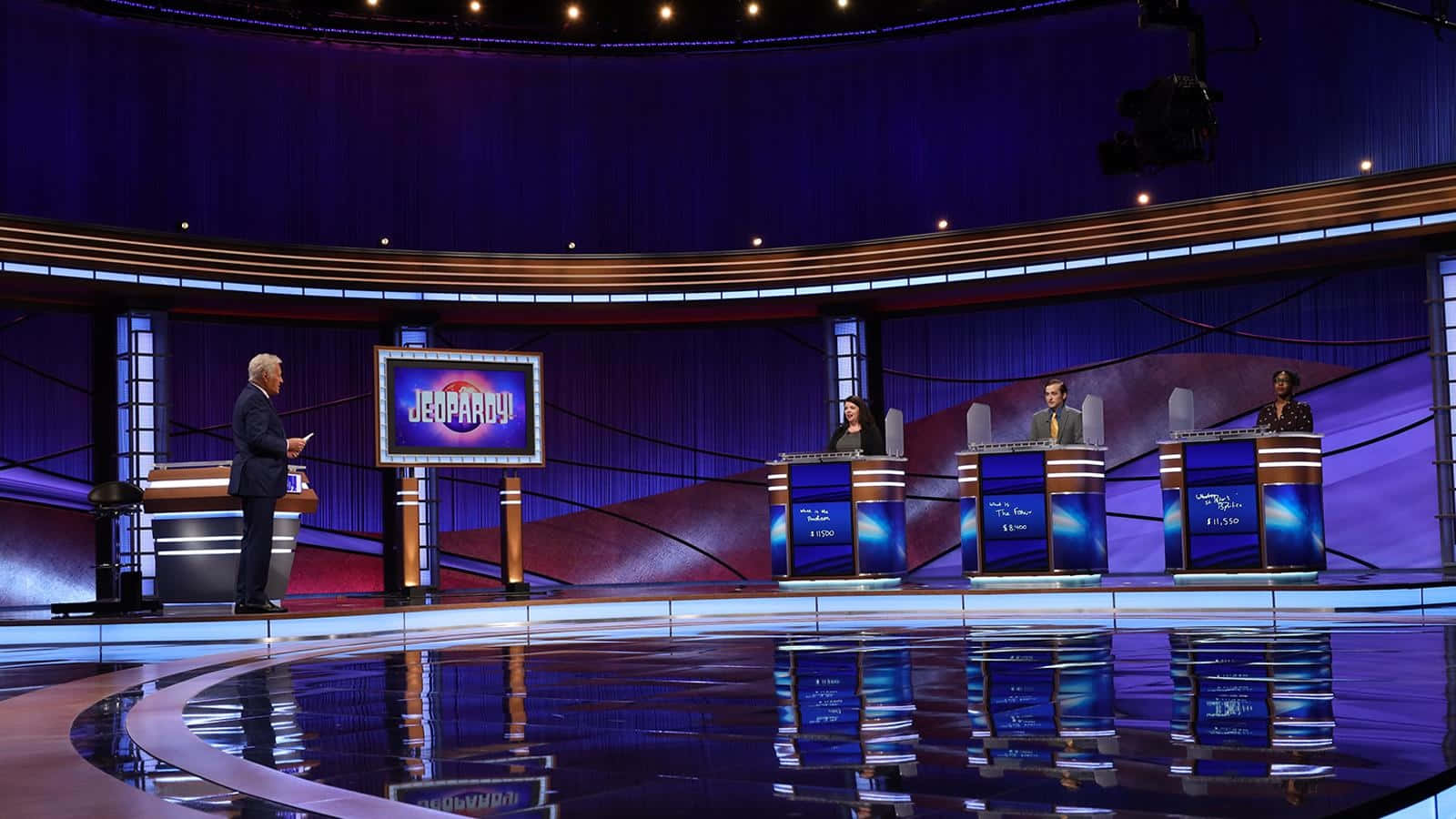 The Stage Of The Jeopardy Show With Three People On Stage