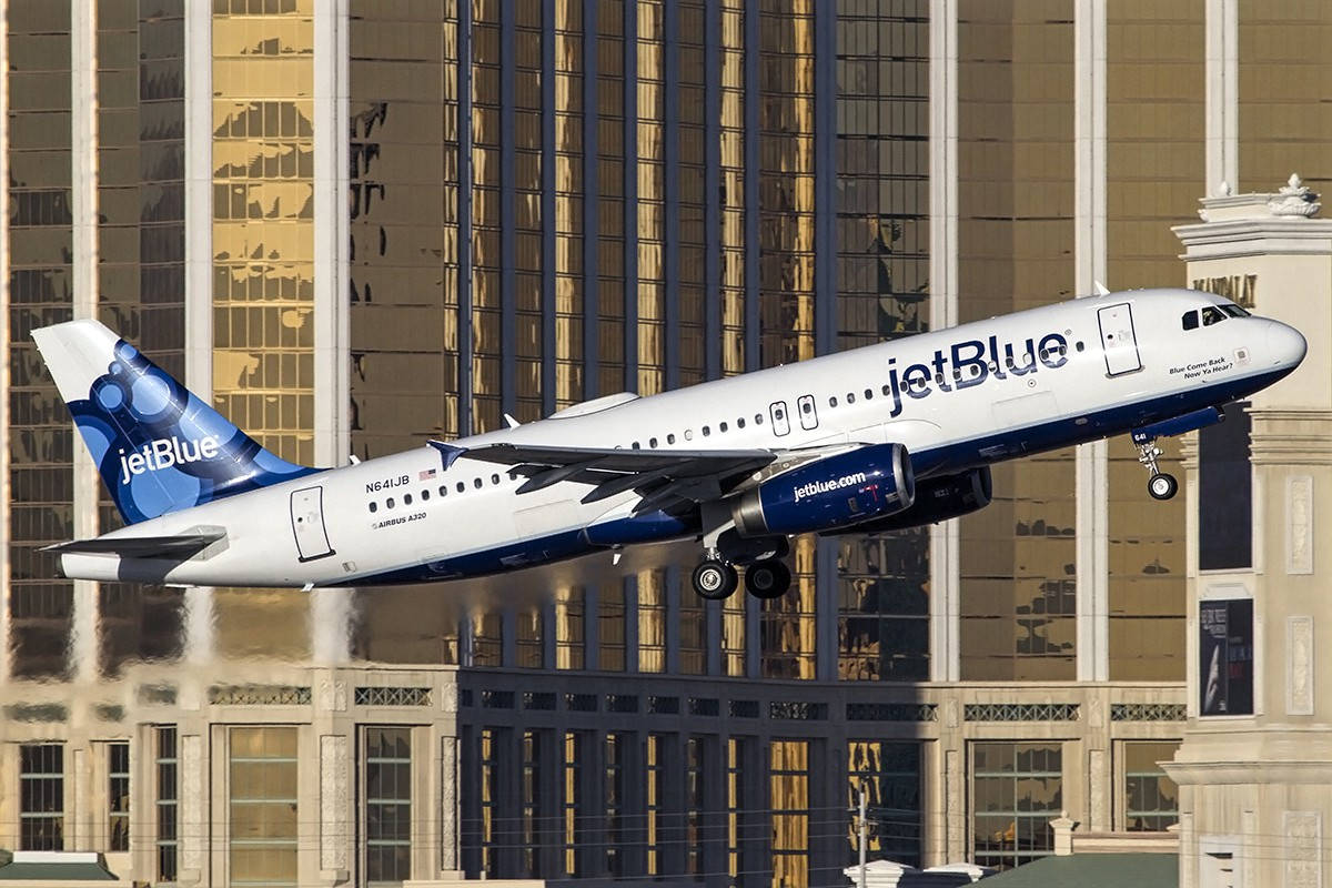 JetBlue flyvemaskine ved byens bygninger tapet Wallpaper