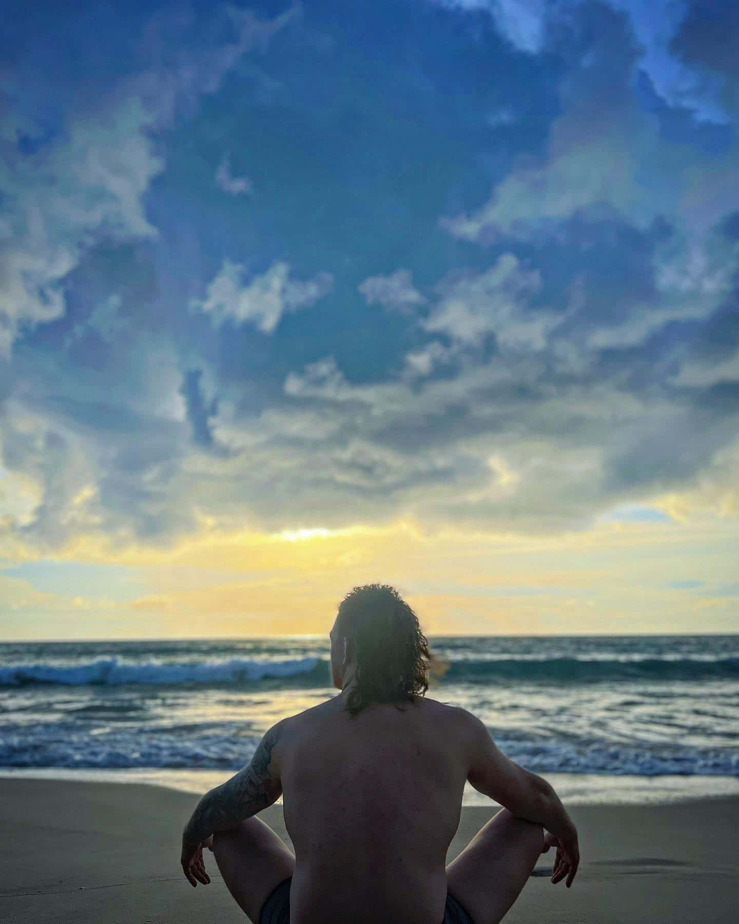 Jimmy Crute sidder på stranden under blå himmel Wallpaper