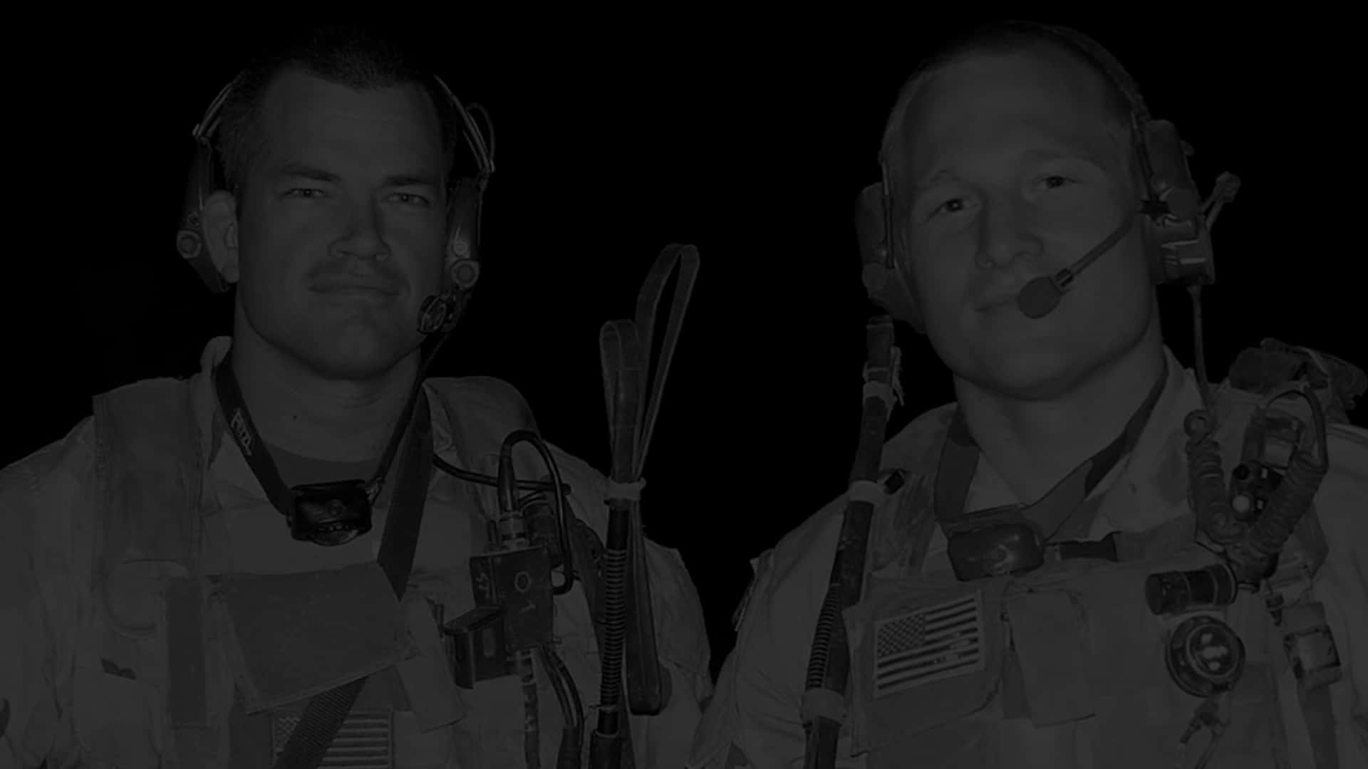 Two Men In Military Uniforms Standing In A Dark Room Wallpaper
