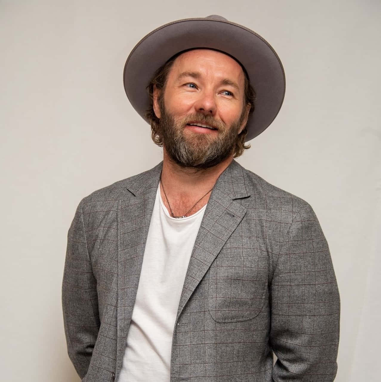 Joel Edgerton Smilingin Hatand Grey Suit Wallpaper