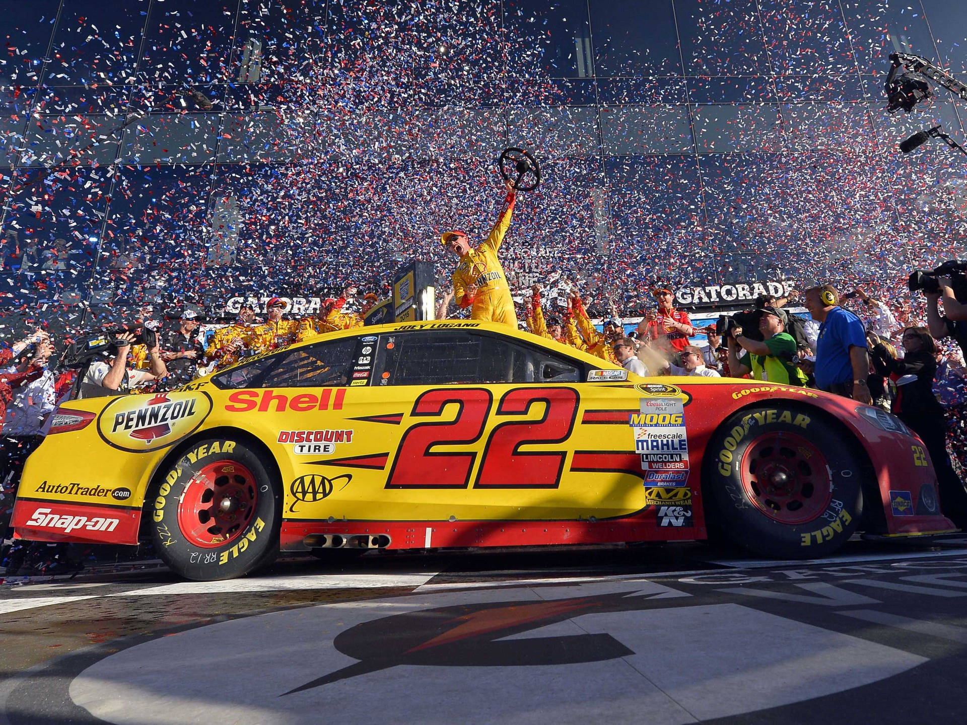 Joey Logano celebrating his victory with confetti at the race track Wallpaper