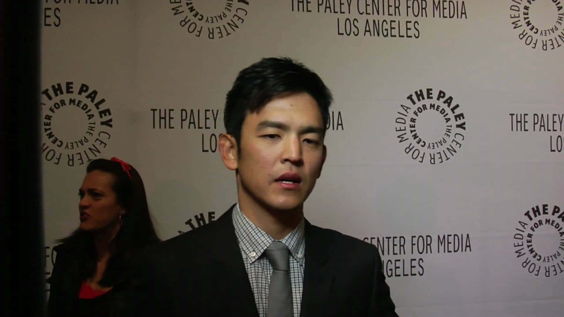 John Cho posing with a confident and charming smile Wallpaper