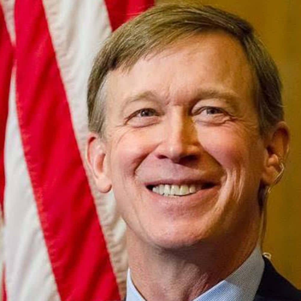 Caption: "John Hickenlooper Smiling in Front of a Red and White Flag" Wallpaper