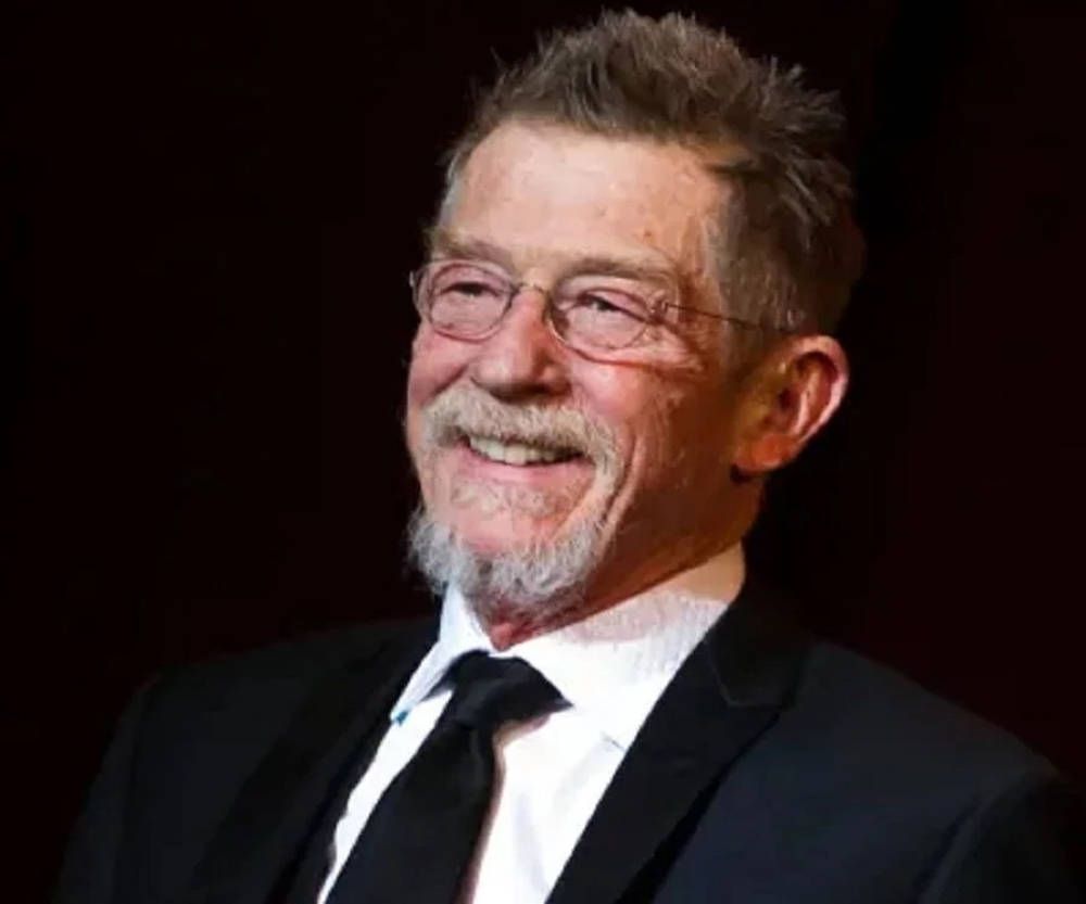 John Hurt smilende jakkesæt og briller tapet Wallpaper