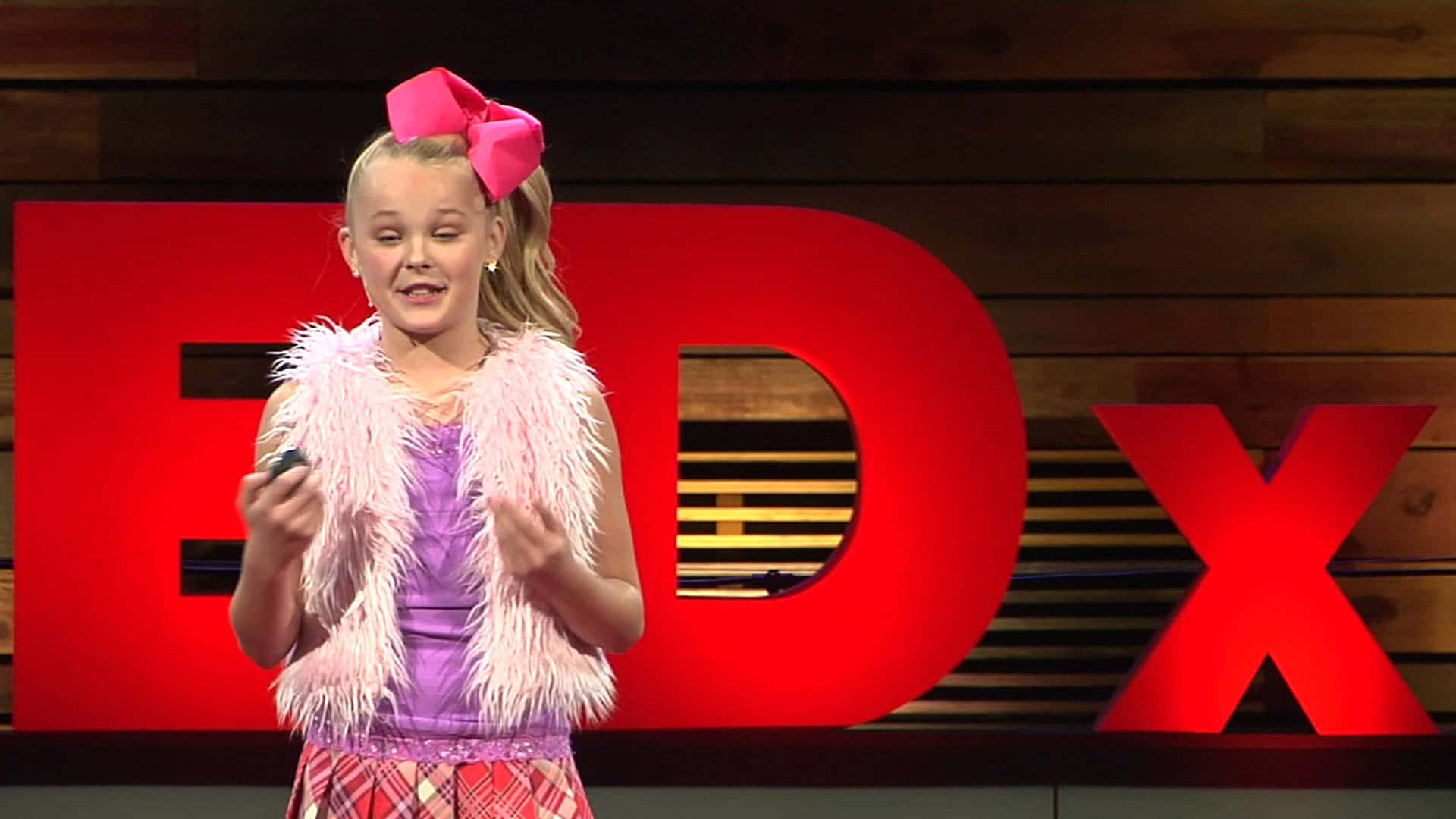 Jojo Siwa rocks out on stage with her signature dad hat and rainbow colored bow!