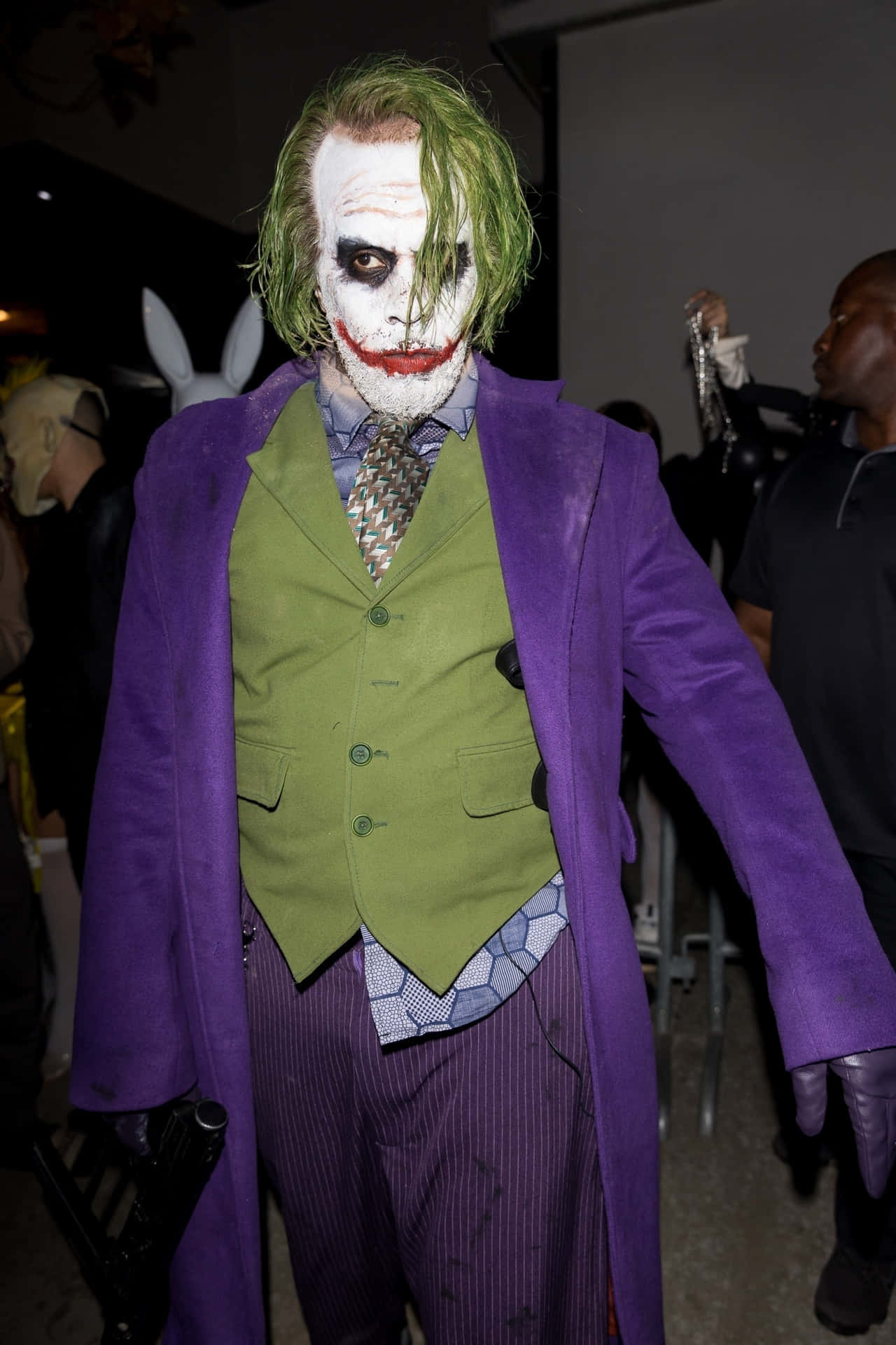 En mand iført joker-kostume griner ondsindet.