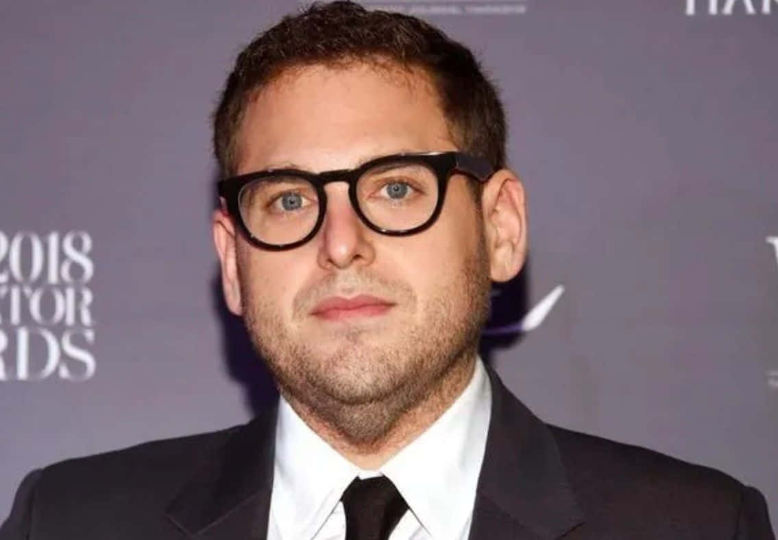Jonah Hill looking suave in a classic black suit Wallpaper