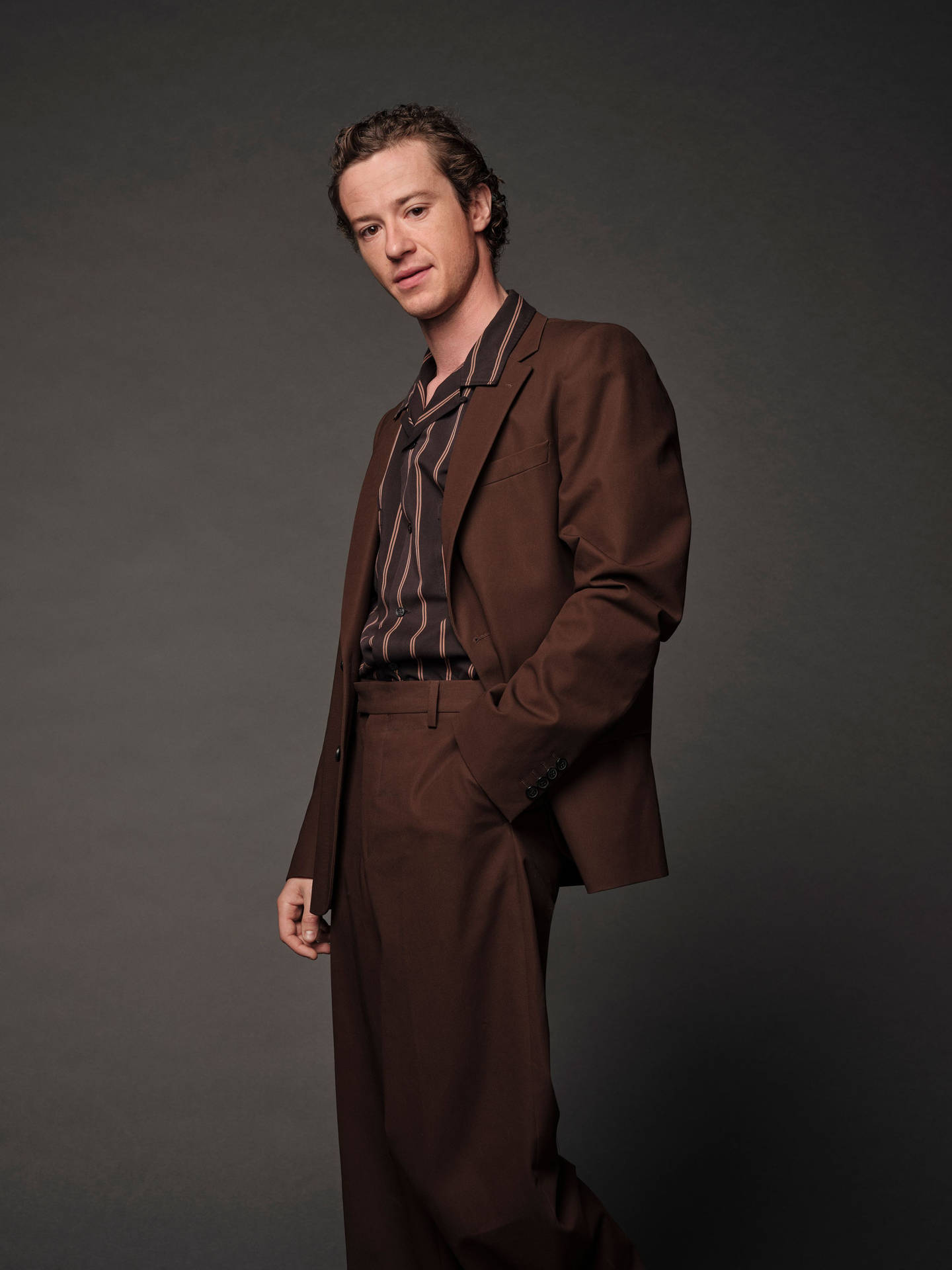 Joseph Quinn In Brown Suit Wallpaper