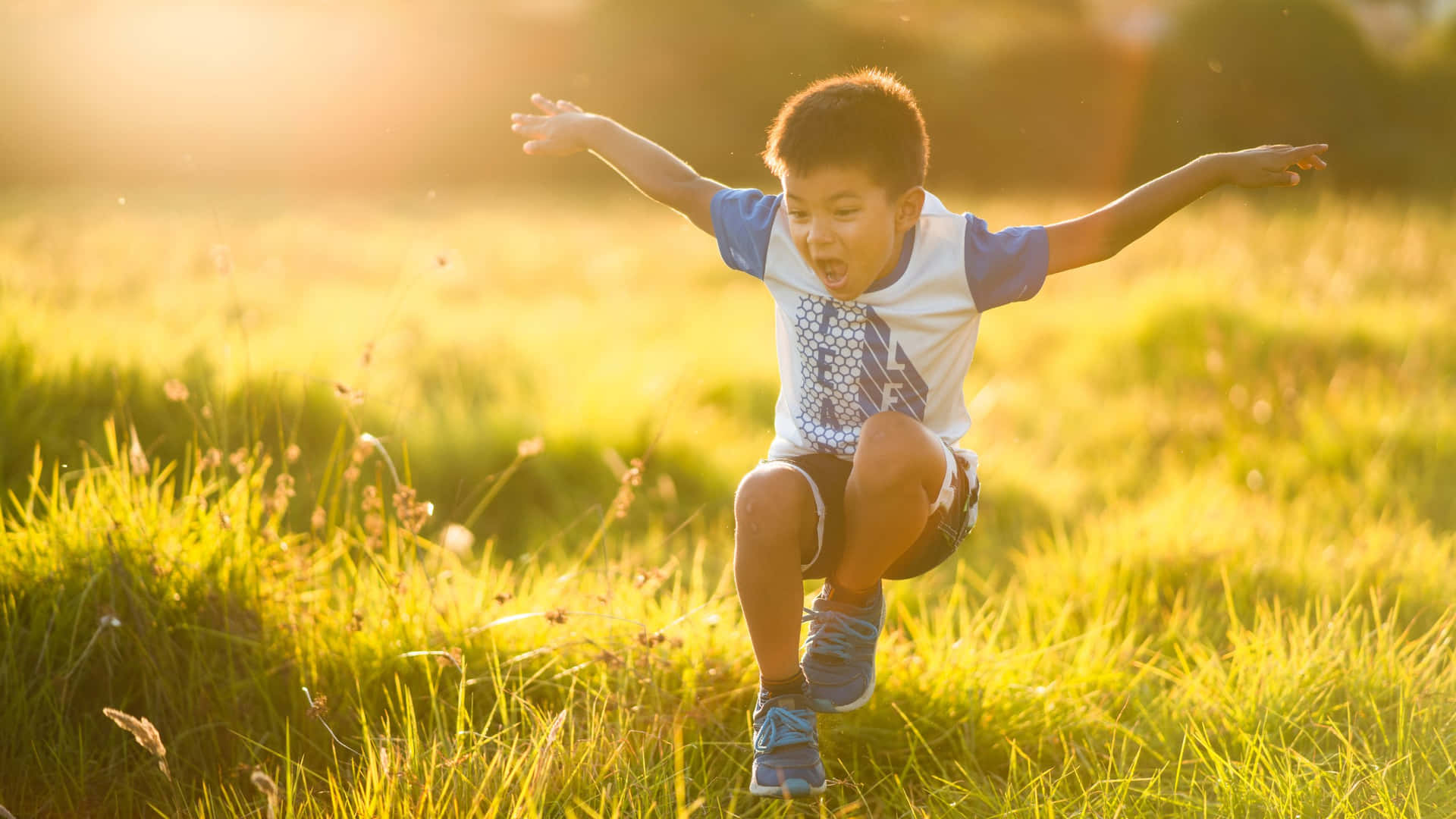 Joyful Boy Playing In Sunlit Field.jpg Wallpaper