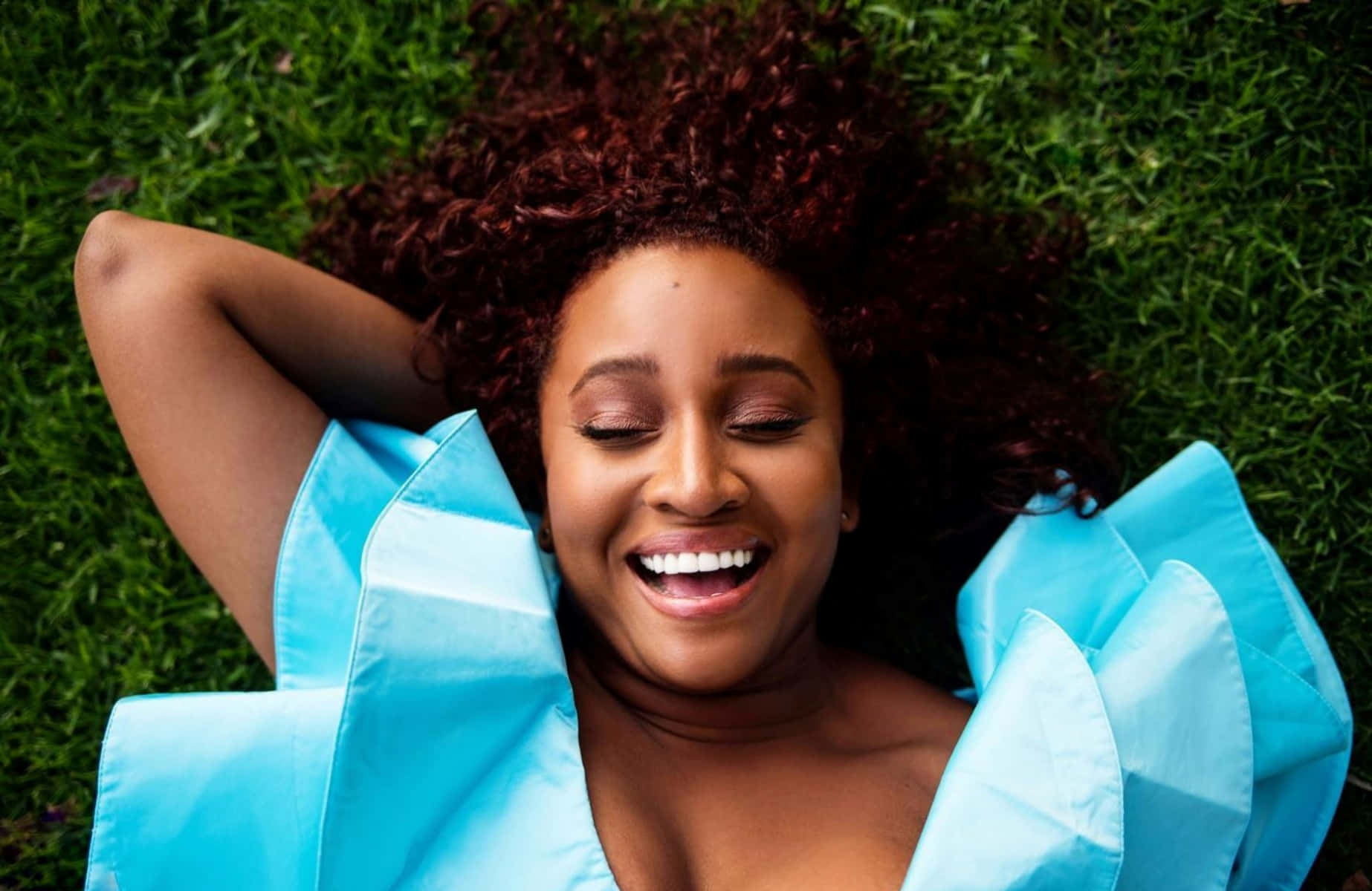 Joyful Woman Lyingon Grass With Blue Pillow Wallpaper