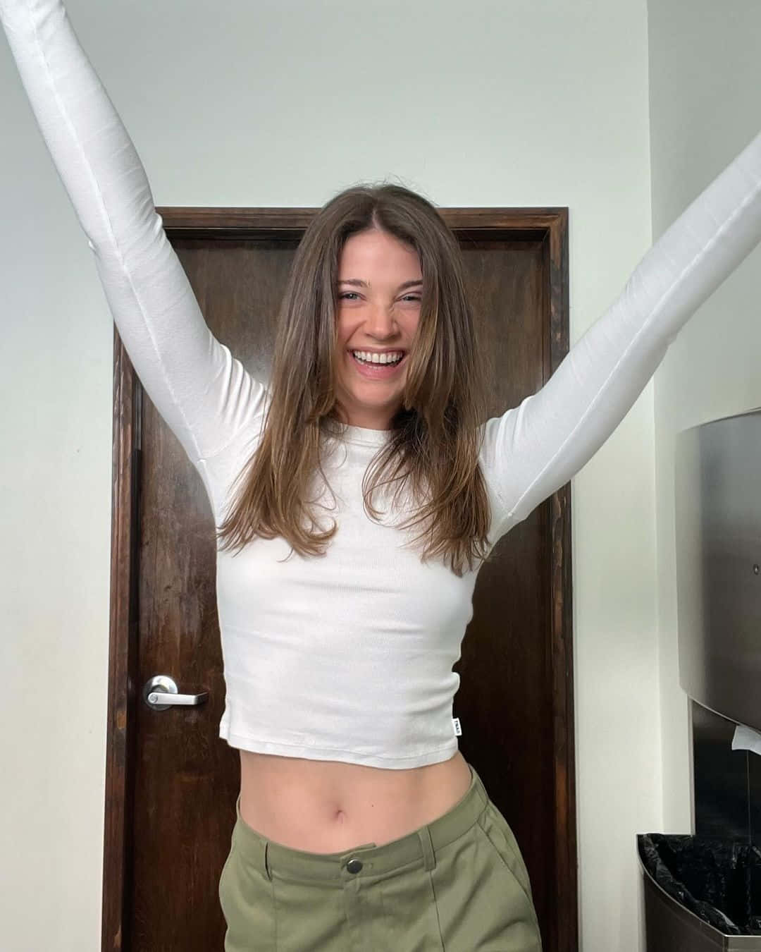 Joyful Woman Raising Armsin Casual Outfit Wallpaper