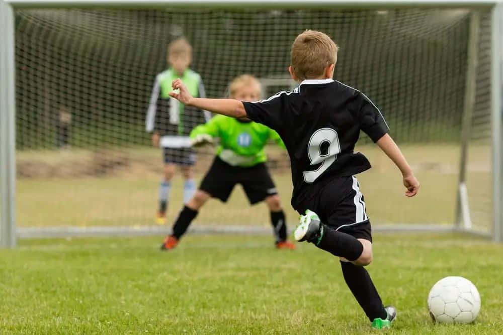 Joyful Young Boy Celebrating A Goal In Soccer Game Wallpaper