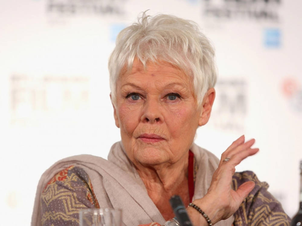Judi Dench striking a pose with a playful hand gesture Wallpaper