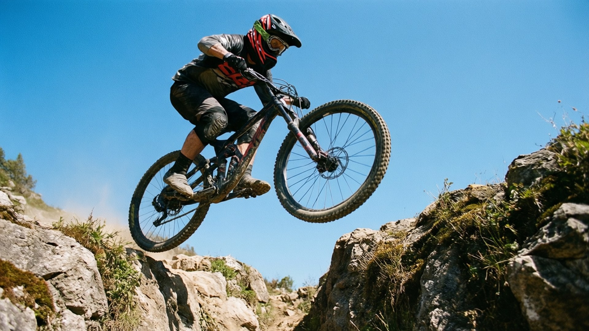 Sprong over de kloof Achtergronden — Een mountainbiker die lucht vangt terwijl hij over een rotsachtige kloof springt.