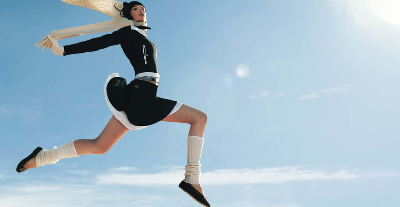 A Woman In A Black And White Dress Jumping In The Air