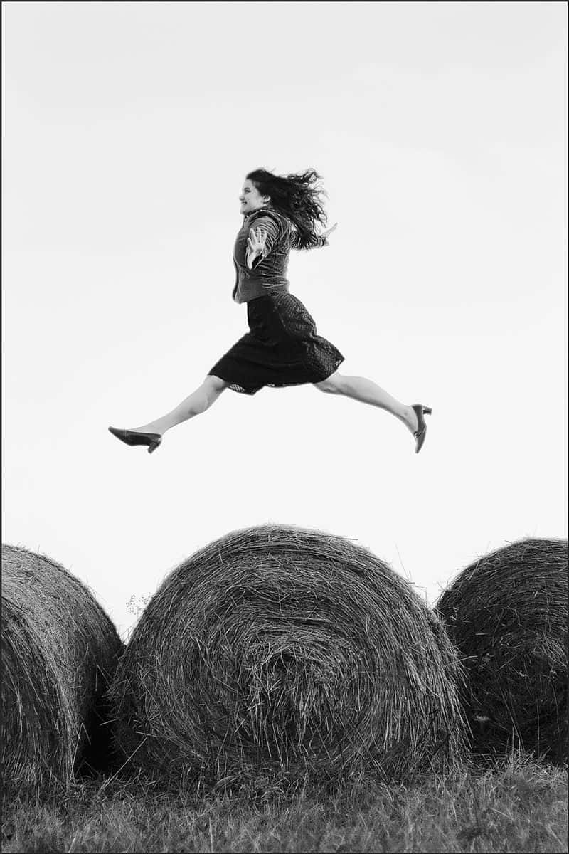 A Woman Jumping Over Hay Bales