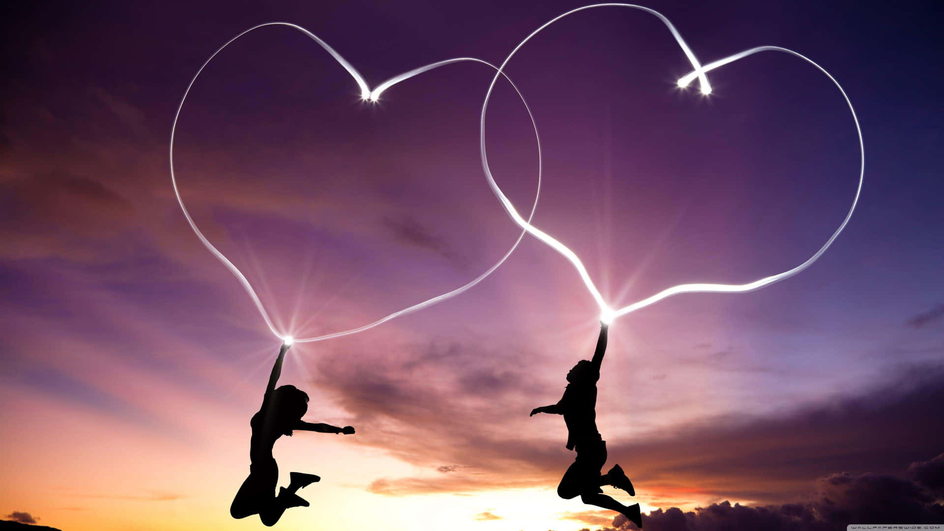 Jumping Couple With Corresponding Light Hearts Wallpaper
