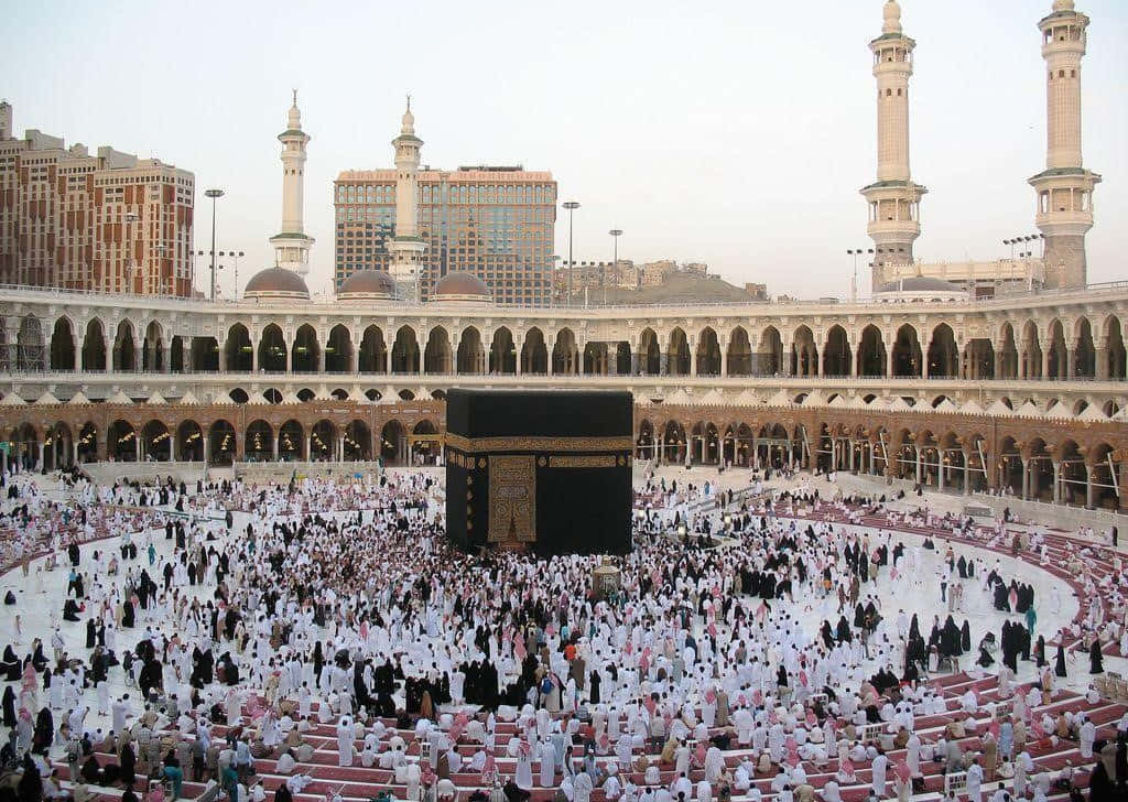 A Large Group Of People Are Standing Around A Kaaba