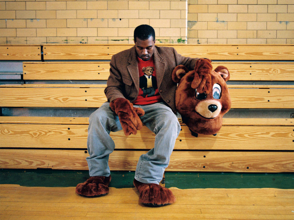 Kanye West Bear Wearing Mascot On Bleachers Background