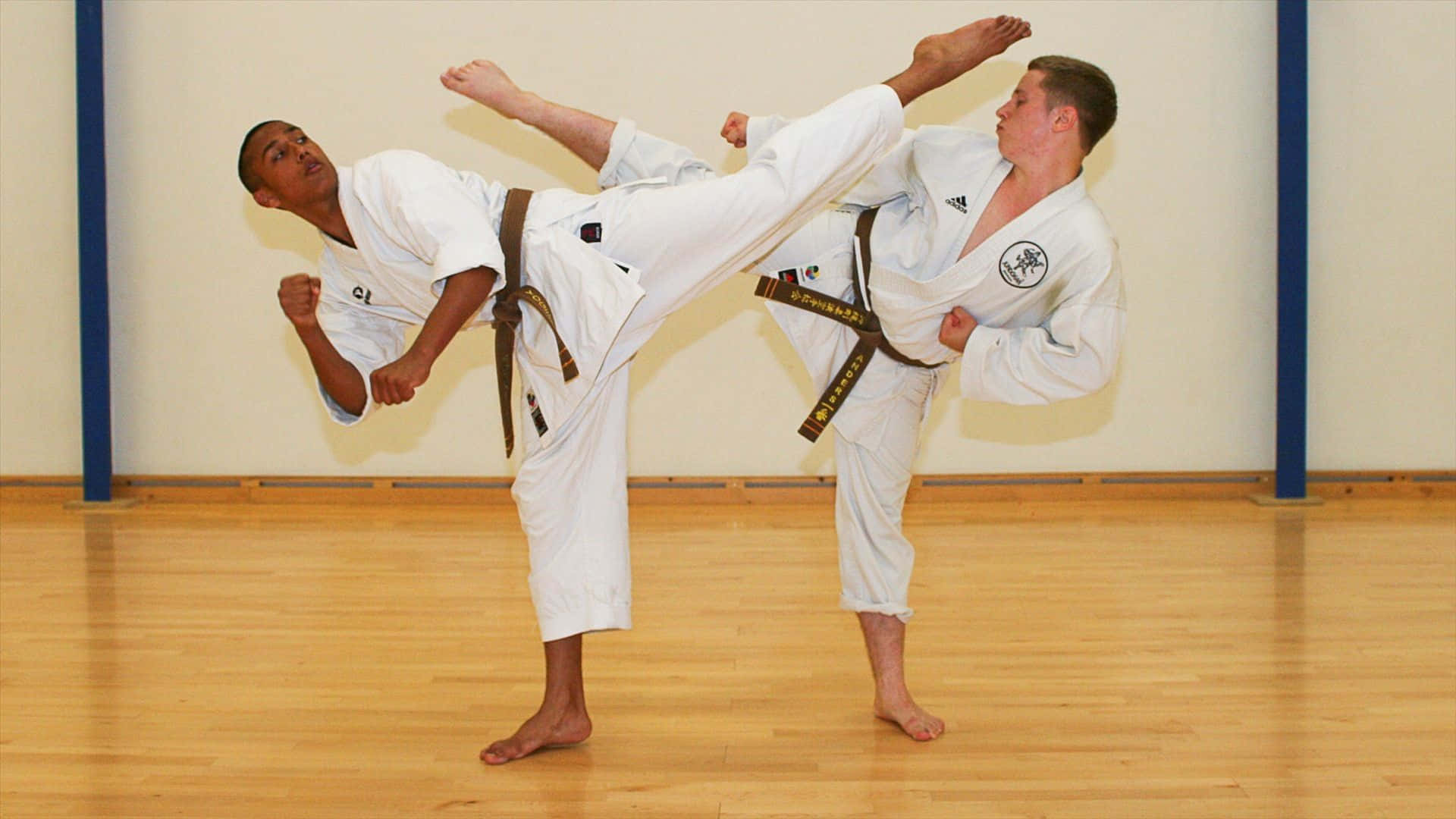 Two Men In White Karate Uniforms Doing A Kick