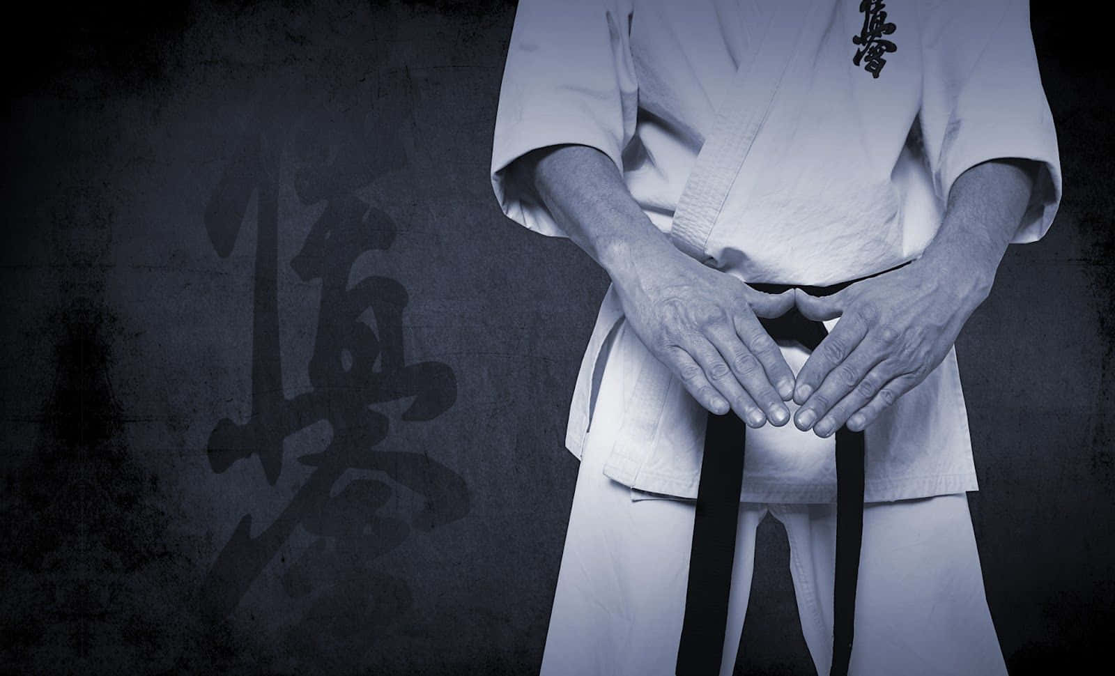 A Man In A Karate Uniform Holding His Hands Up